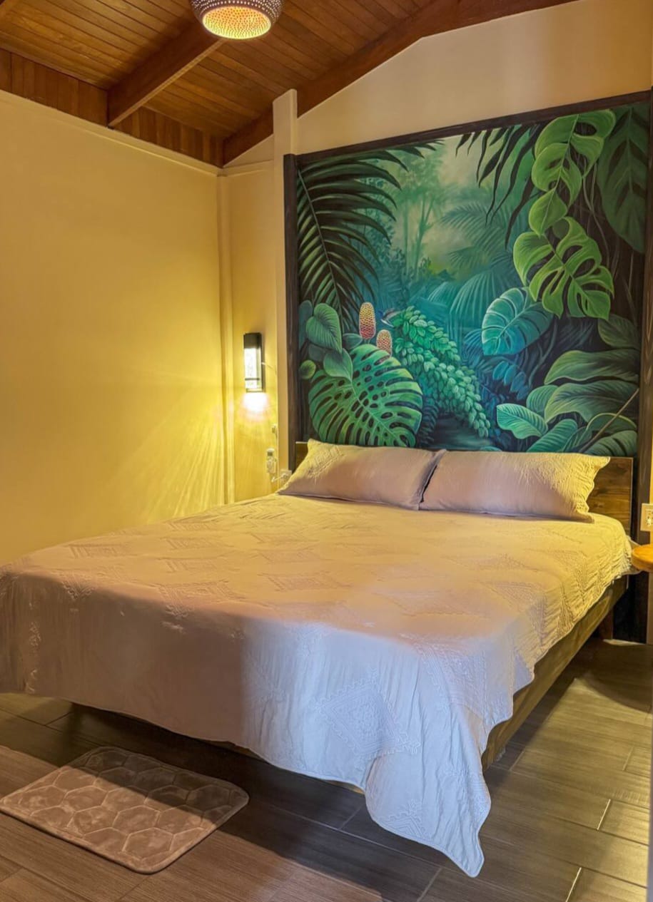 King bed with a floor-to-ceiling jungle mural headboard